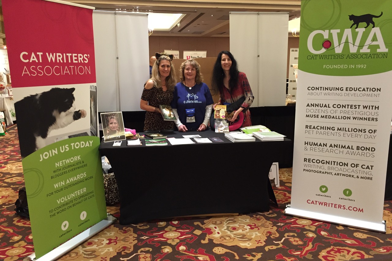 Cat authors Mary-Marci Kladnik, Janiss Garza, and Deb Barnes manning the Cat Writers' Association booth at BlogPaws 2015.
